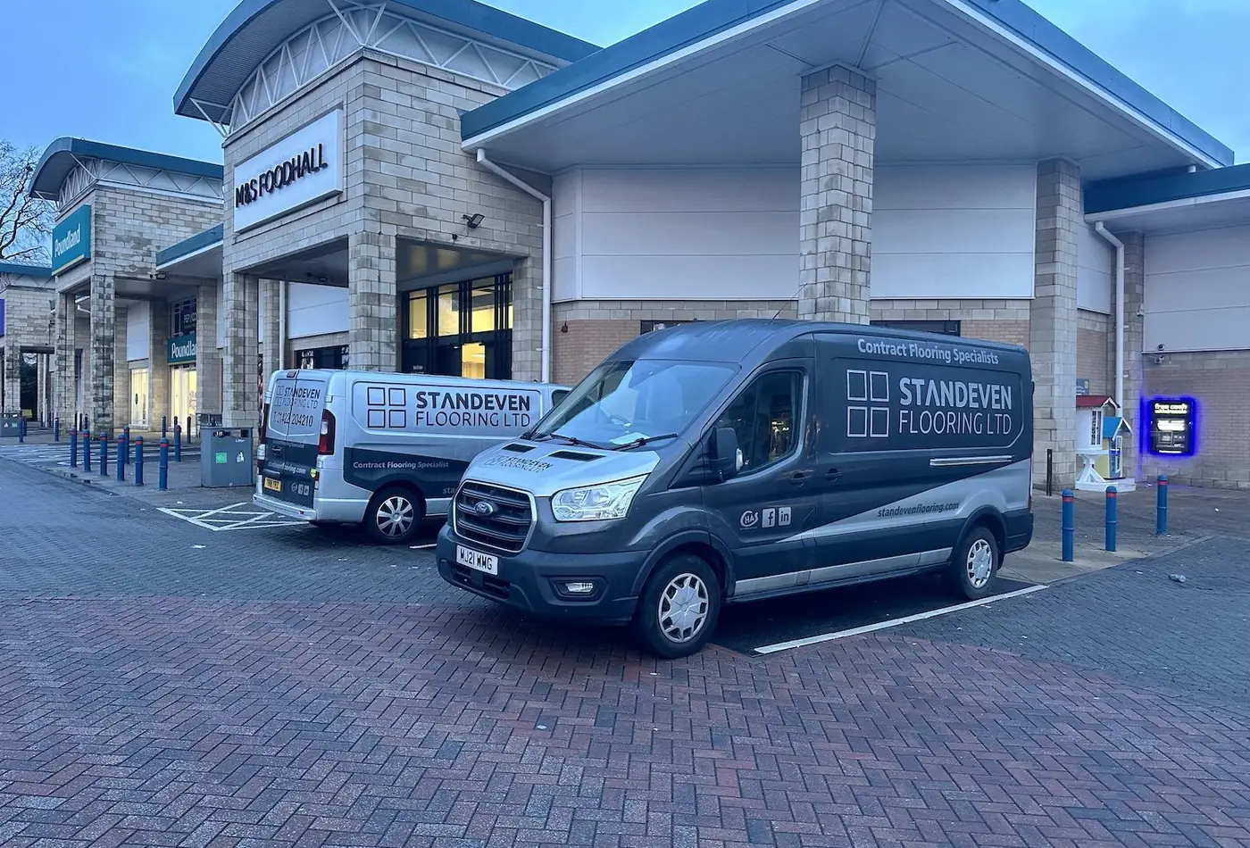 Two branded Standeven Flooring vans parked outside an M and S Foodhall at dusk, the lead photo on their Leeds page